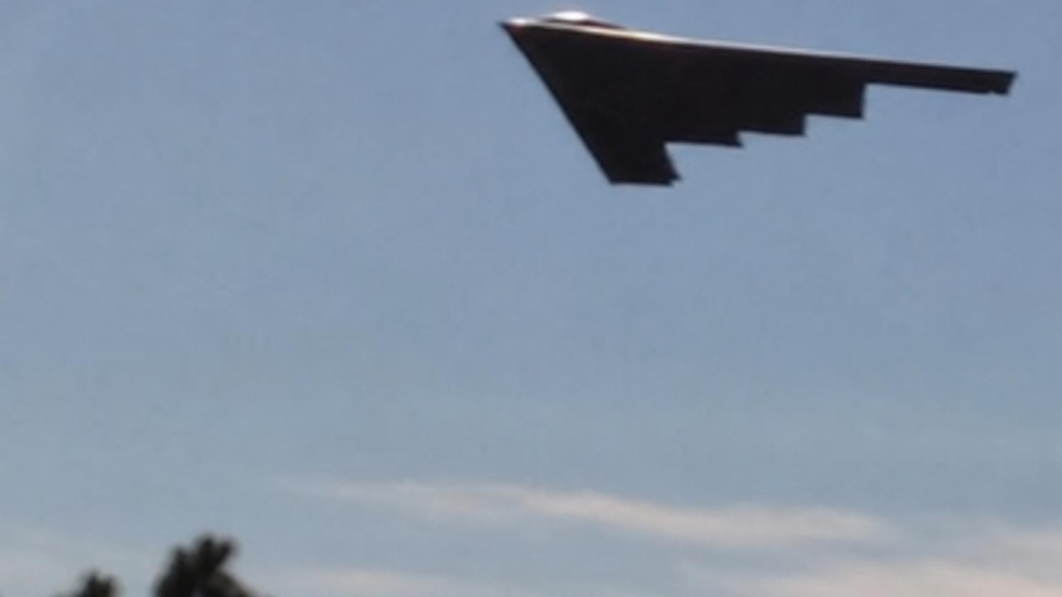 A shadowy silhouette of the wing-shaped aircraft is captured mid-fl…
