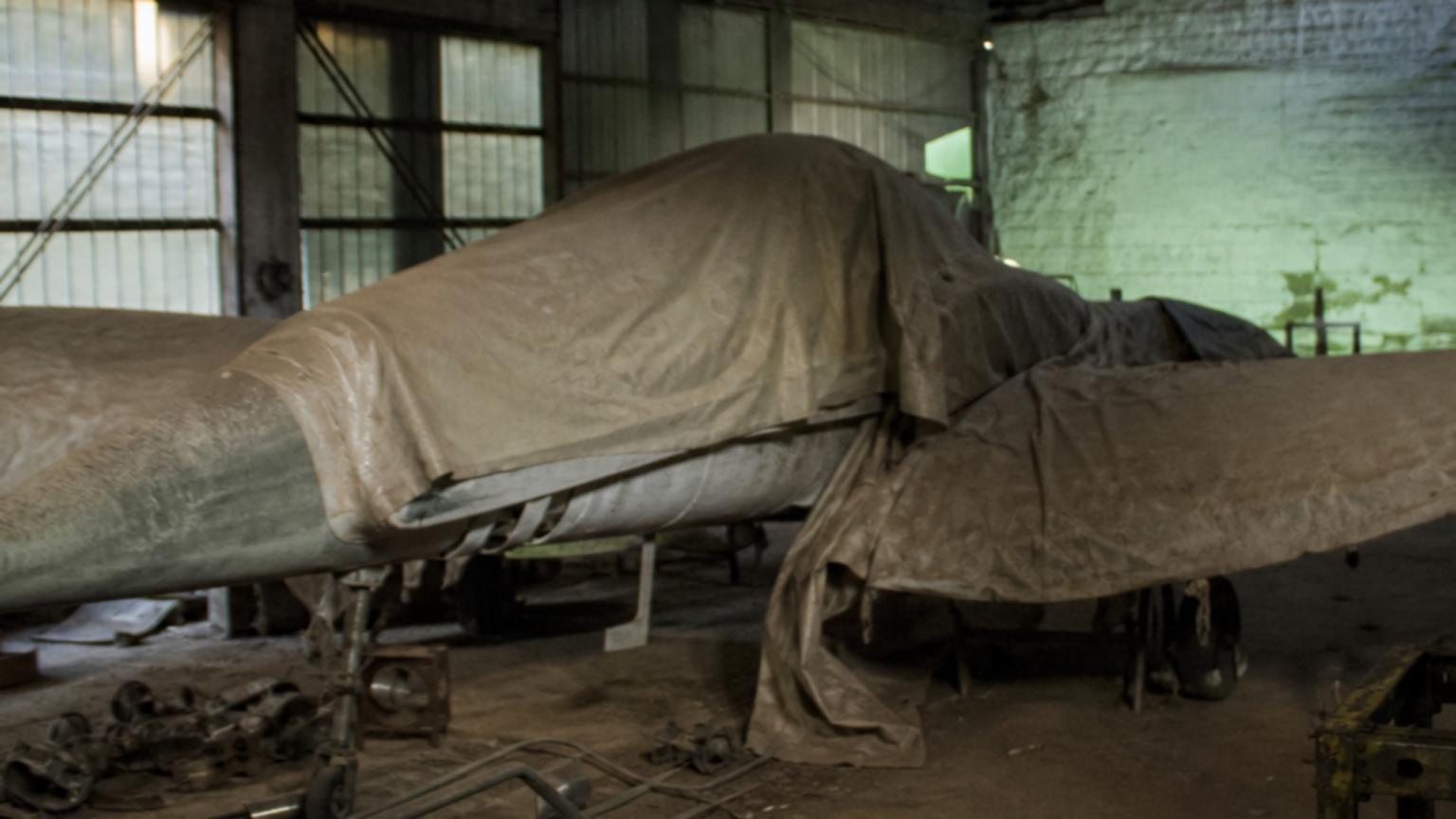 A dusty, abandoned hangar in Córdoba, where the fighter sits cloake…